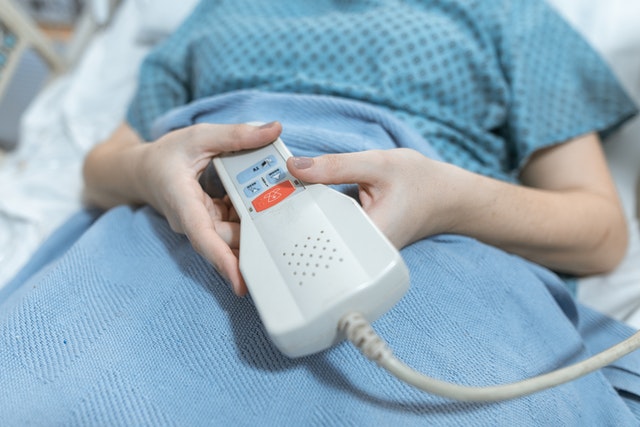 person holding remote for nurse call systems in hospital bed